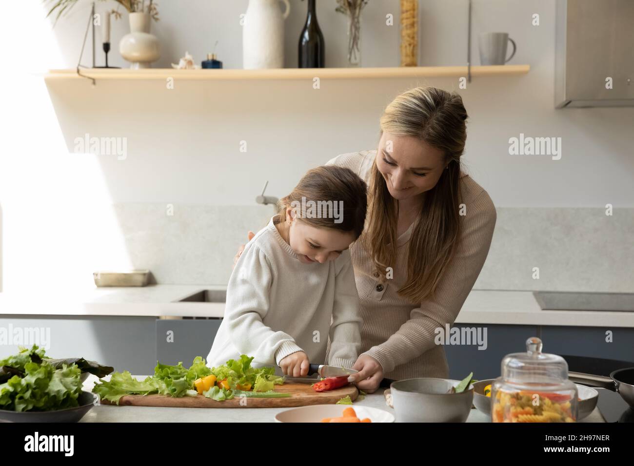 Felice madre giovane insegnando la cottura della figlia piccola. Foto Stock