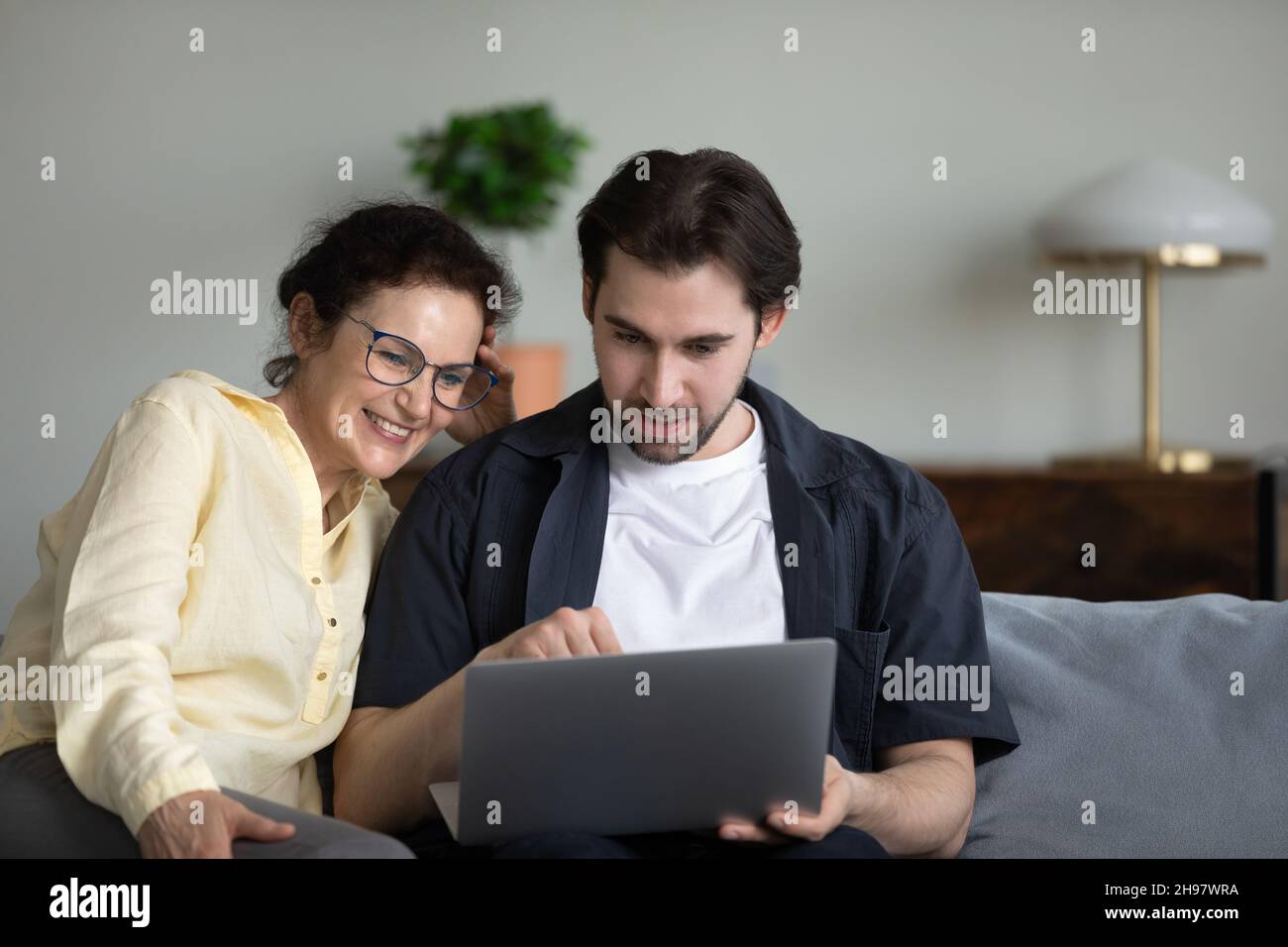 Figlio adulto che insegna mamma matura a utilizzare l'app virtuale online Foto Stock