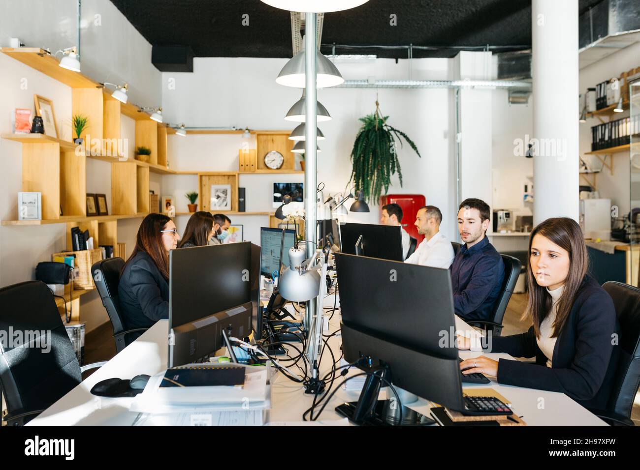 Persone che condividono l'ufficio e lavorano su una scrivania con computer Foto Stock