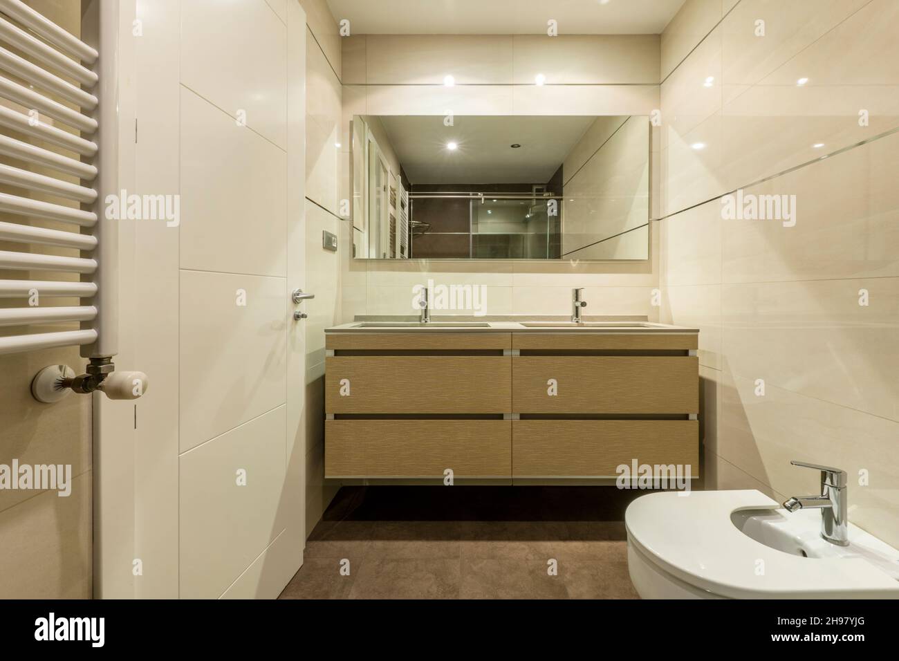 Bagno moderno in tonalità crema e marrone con due rubinetti e due lavandini in un appartamento in affitto per le vacanze Foto Stock