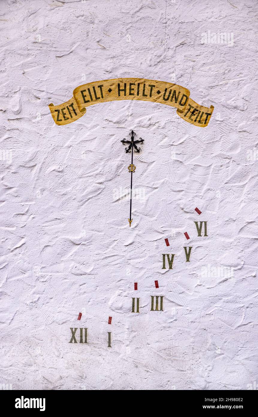 Meridiana con motto in tedesco ZEIT EILT HEILT UND TEILT (IL TEMPO CORRE GUARISCE E DIVIDE) su un muro di casa bianca. Foto Stock