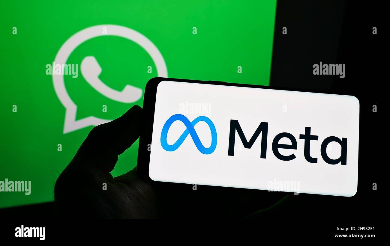 Persona che tiene uno smartphone con la scritta della società tecnologica statunitense Meta Platforms Inc. Sullo schermo davanti al logo WhatsApp. Mettere a fuoco sul display del telefono. Foto Stock
