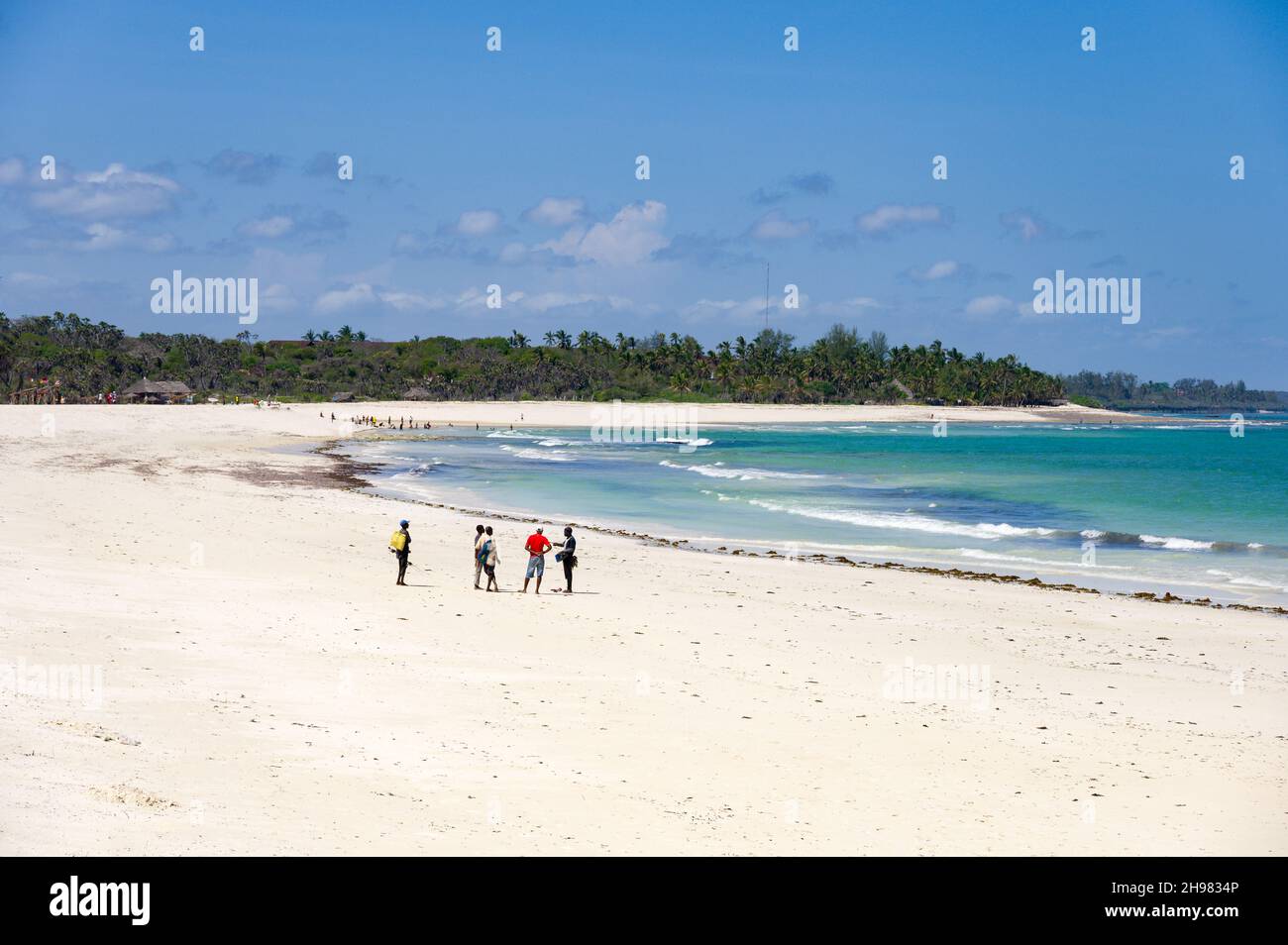 Pescatori locali in piedi sulla spiaggia che parlano vicino all'oceano, Diani, Kenya Foto Stock