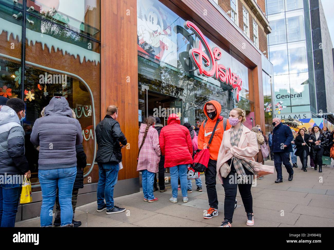 Gli acquirenti di Natale si accodano per entrare nel negozio Disney sulla Oxford Street di Londra. Il governo del Regno Unito ha riimposto misure che lo rendono un requisito legale per indossare i rivestimenti per il viso nei negozi e sui trasporti pubblici, a meno che non sia esente dal 30 novembre in mezzo a preoccupazioni per la variante Omicron del covid-19. Foto Stock