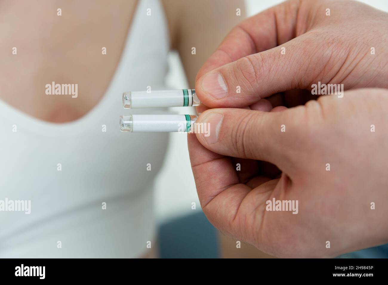 Il medico tiene in mano piccole fiale. Primo piano della fiala piccola con un vaccino in mano al medico. Provetta per test allergico. Test di allergia Foto Stock