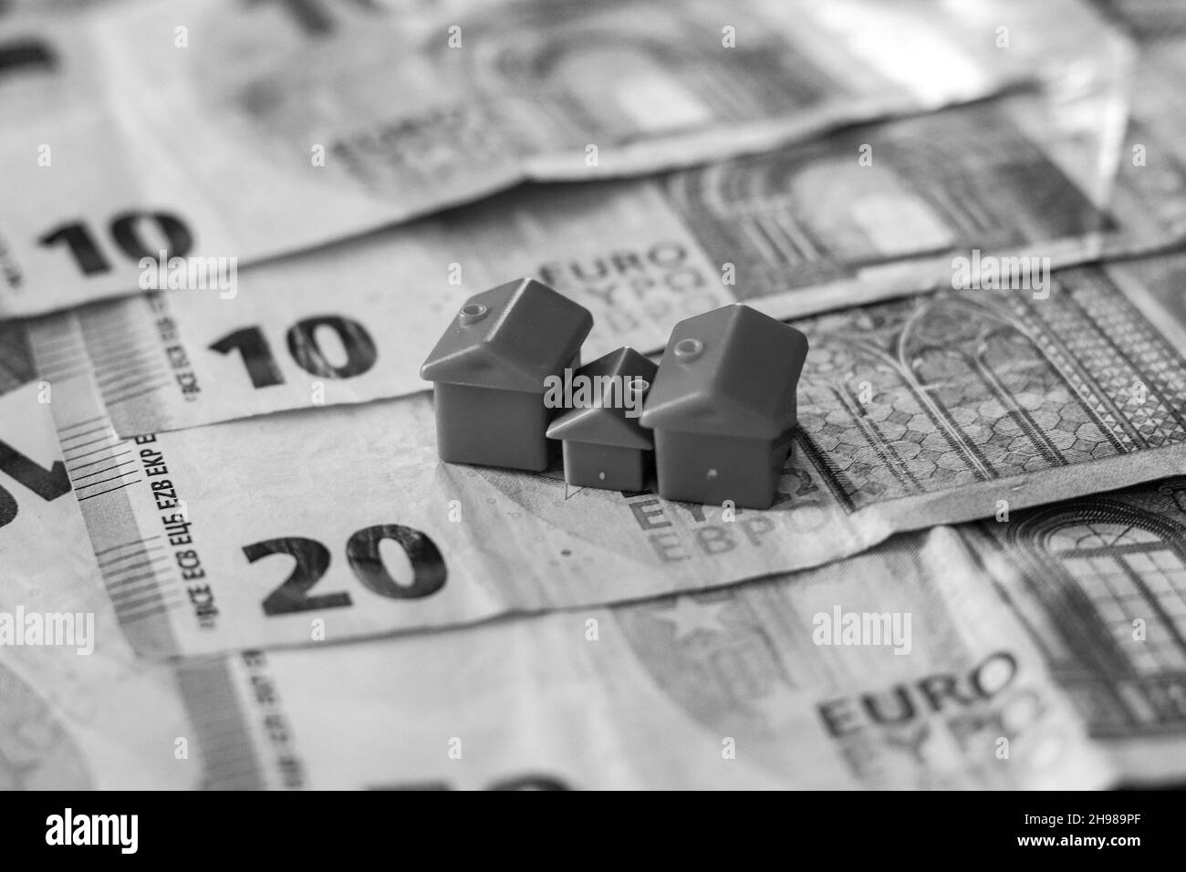 Tavolo coperto con banconote in euro con case in cima. Concetto di investimento immobiliare Foto Stock