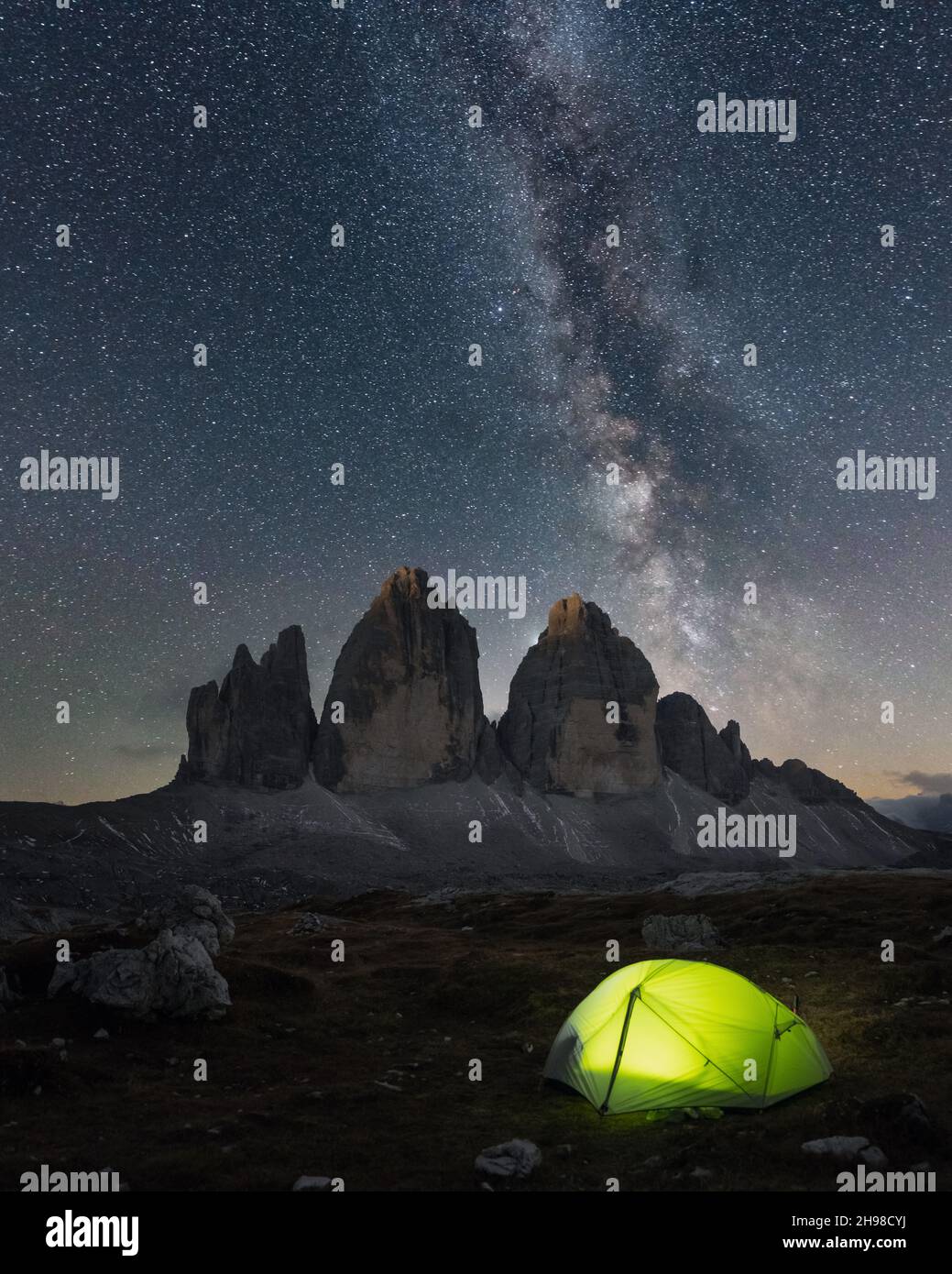 Tenda verde illuminata dall'interno contro lo sfondo di un incredibile cielo stellato e tre cime delle montagne di Lavaredo. Parco Nazionale tre Cime di Lavaredo, Dolomiti, Italia. Fotografia di paesaggio Foto Stock