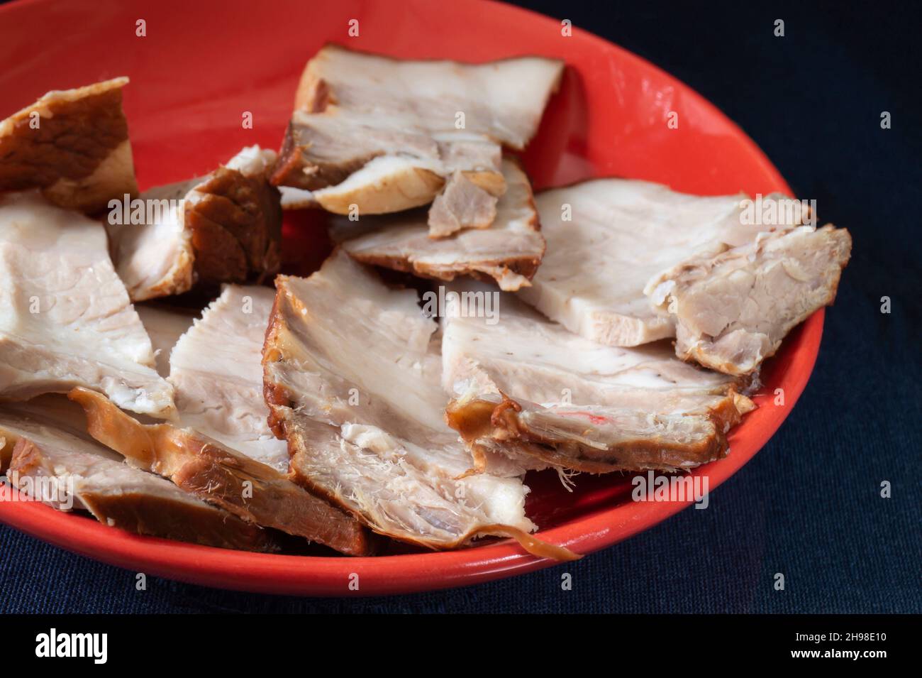 Pancia di maiale in un piatto su sfondo nero. Carne tagliata a pezzi. Foto Stock