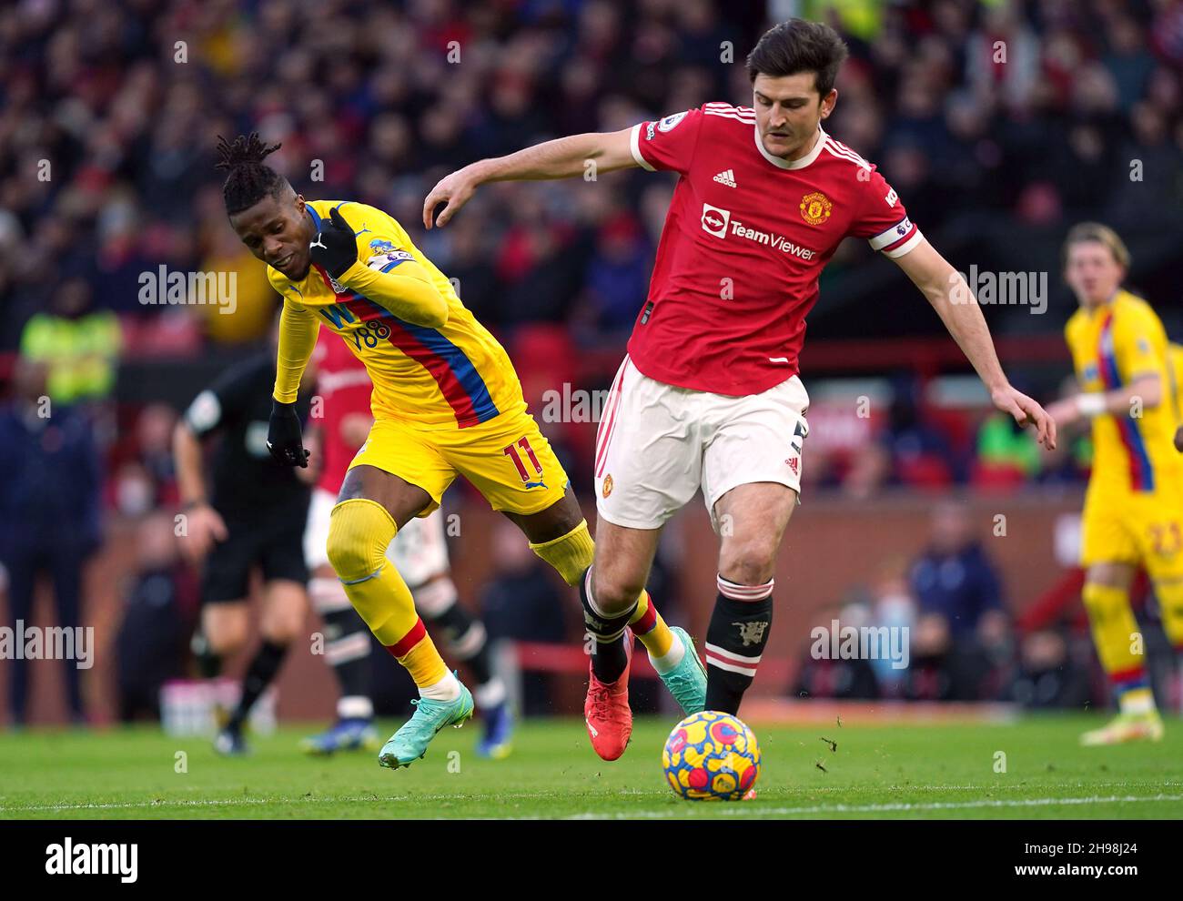 Wilfried Zaha (a sinistra) di Crystal Palace e Harry Maguire del Manchester United combattono per la palla durante la partita della Premier League a Old Trafford, Manchester. Data foto: Domenica 5 dicembre 2021. Foto Stock