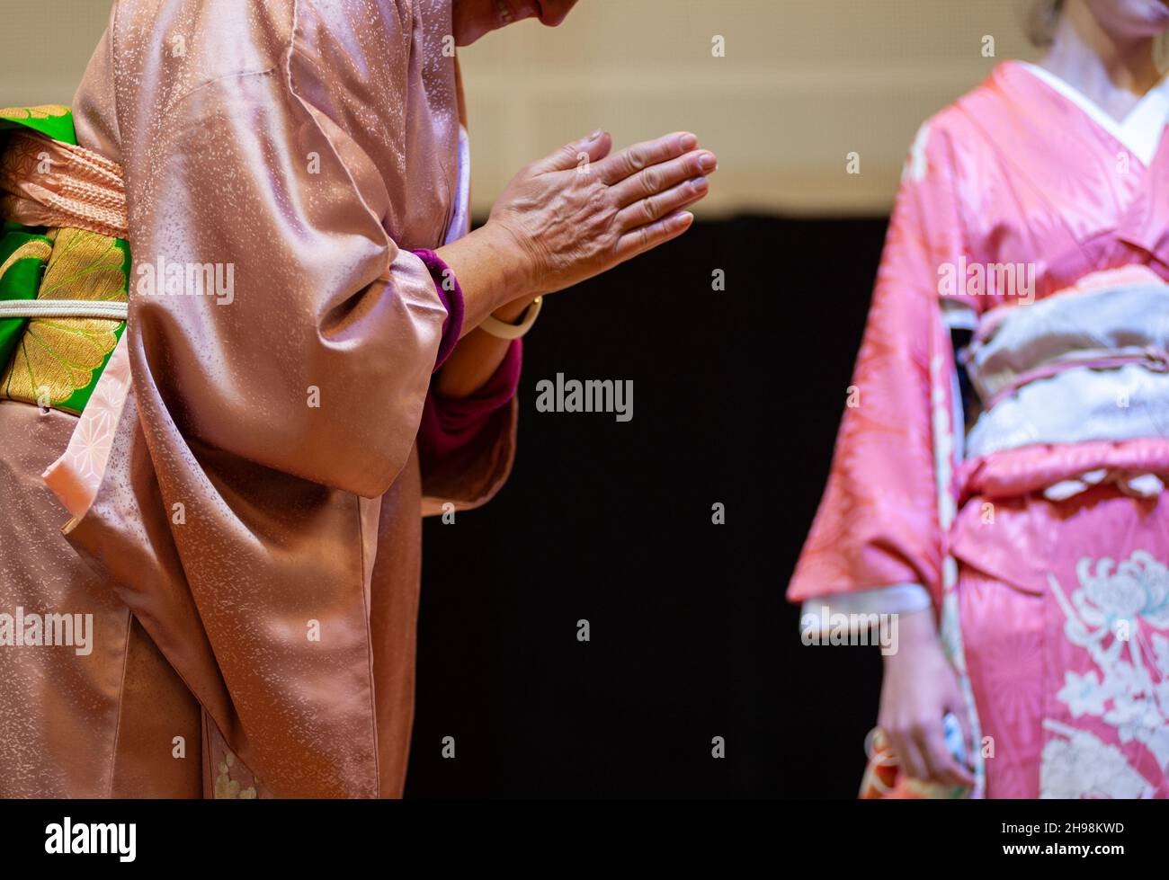 saluto e inchinatura con le mani ripiegate, di una donna giapponese in kimono. Foto Stock