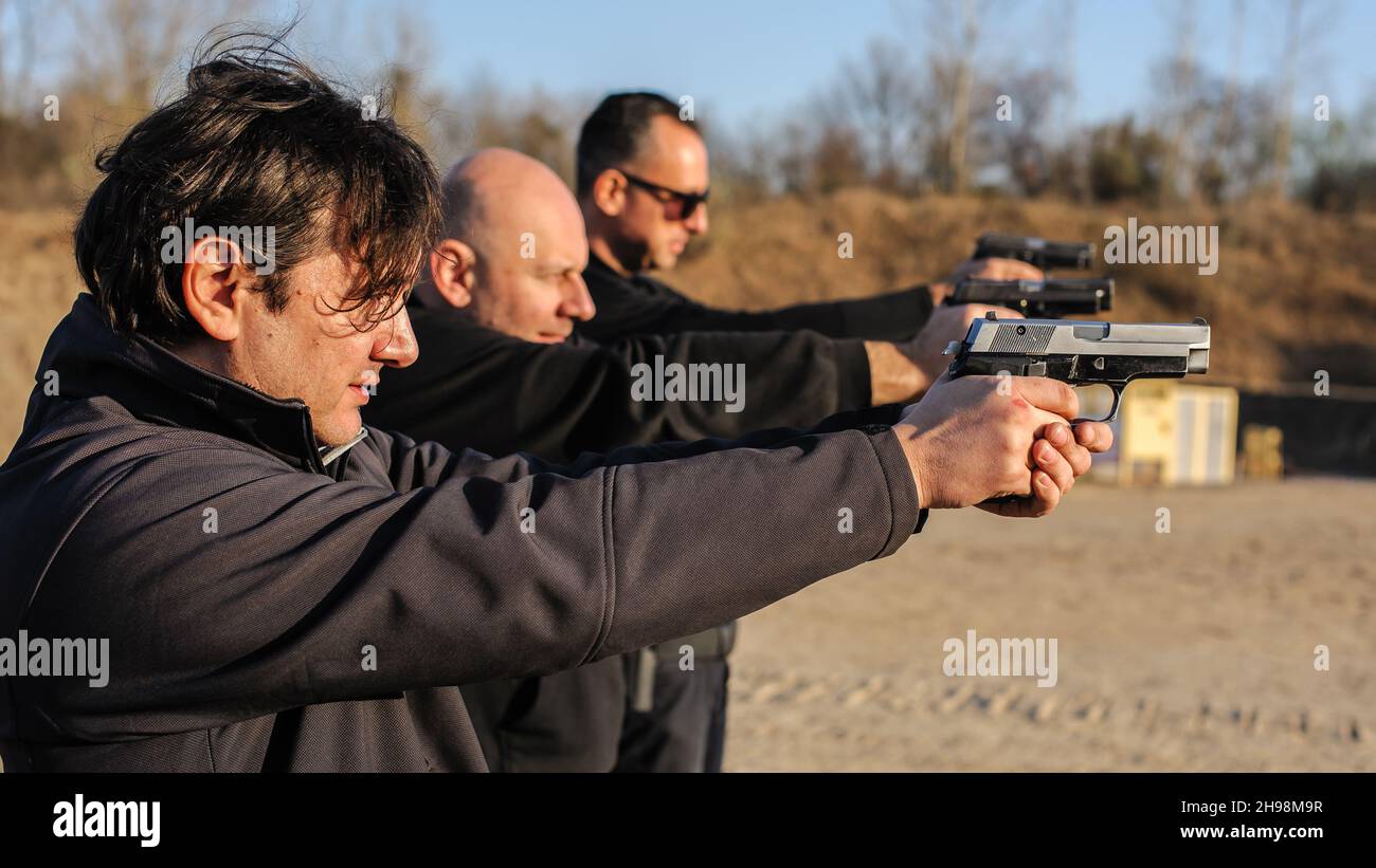 Gruppo di persone pratica sparare pistola su bersaglio su campo di tiro all'aperto. Addestramento delle armi della squadra civile Foto Stock