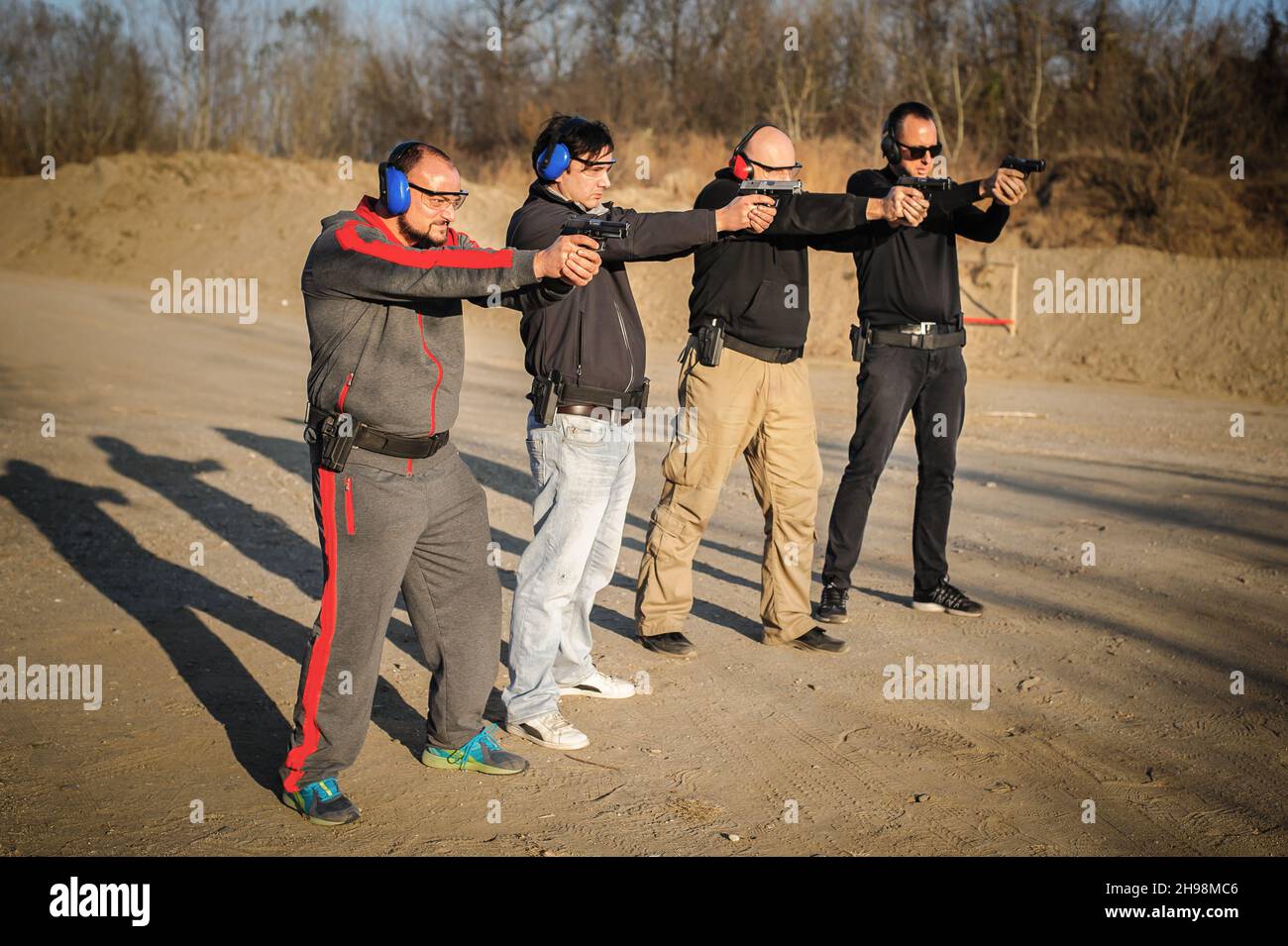 Gruppo di persone pratica sparare pistola su bersaglio su campo di tiro all'aperto. Addestramento delle armi della squadra civile Foto Stock