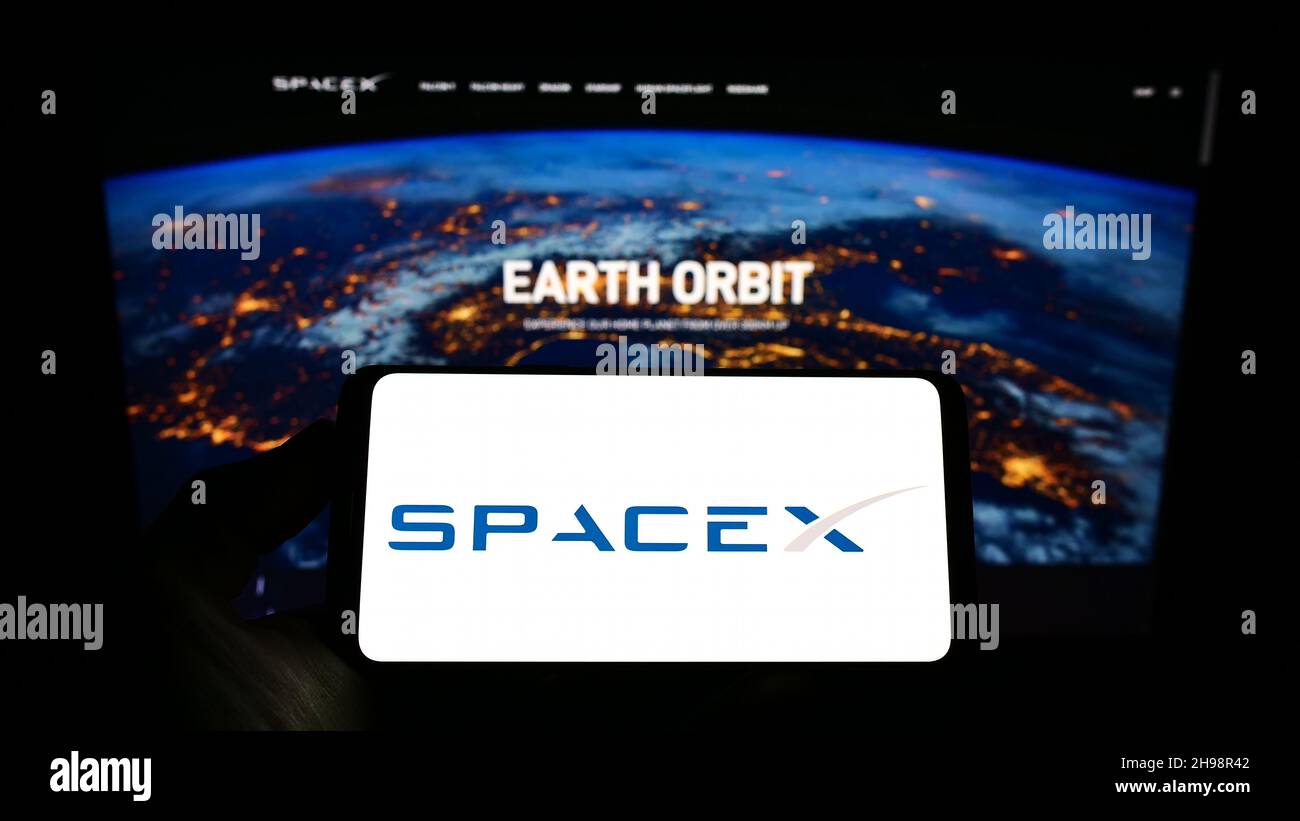 Persona che tiene smartphone con il logo della società Space Exploration Technologies Corp. (SpaceX) sullo schermo di fronte al sito web. Mettere a fuoco sul display del telefono. Foto Stock