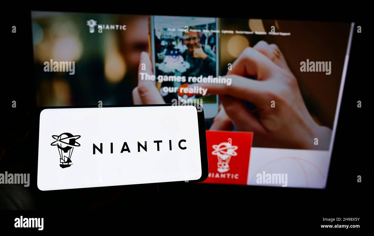 Persona che tiene il telefono cellulare con il logo della società americana di software di gioco Niantic Inc. Sullo schermo di fronte alla pagina web. Mettere a fuoco sul display del telefono. Foto Stock
