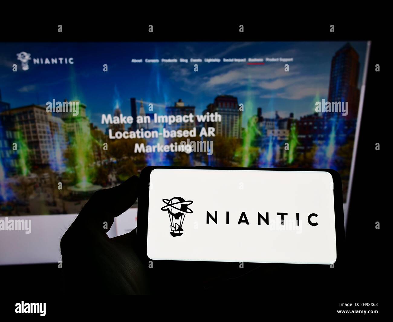 Persona che tiene il cellulare con il logo della società statunitense di software di gioco Niantic Inc. Sullo schermo di fronte al sito web aziendale. Mettere a fuoco sul display del telefono. Foto Stock