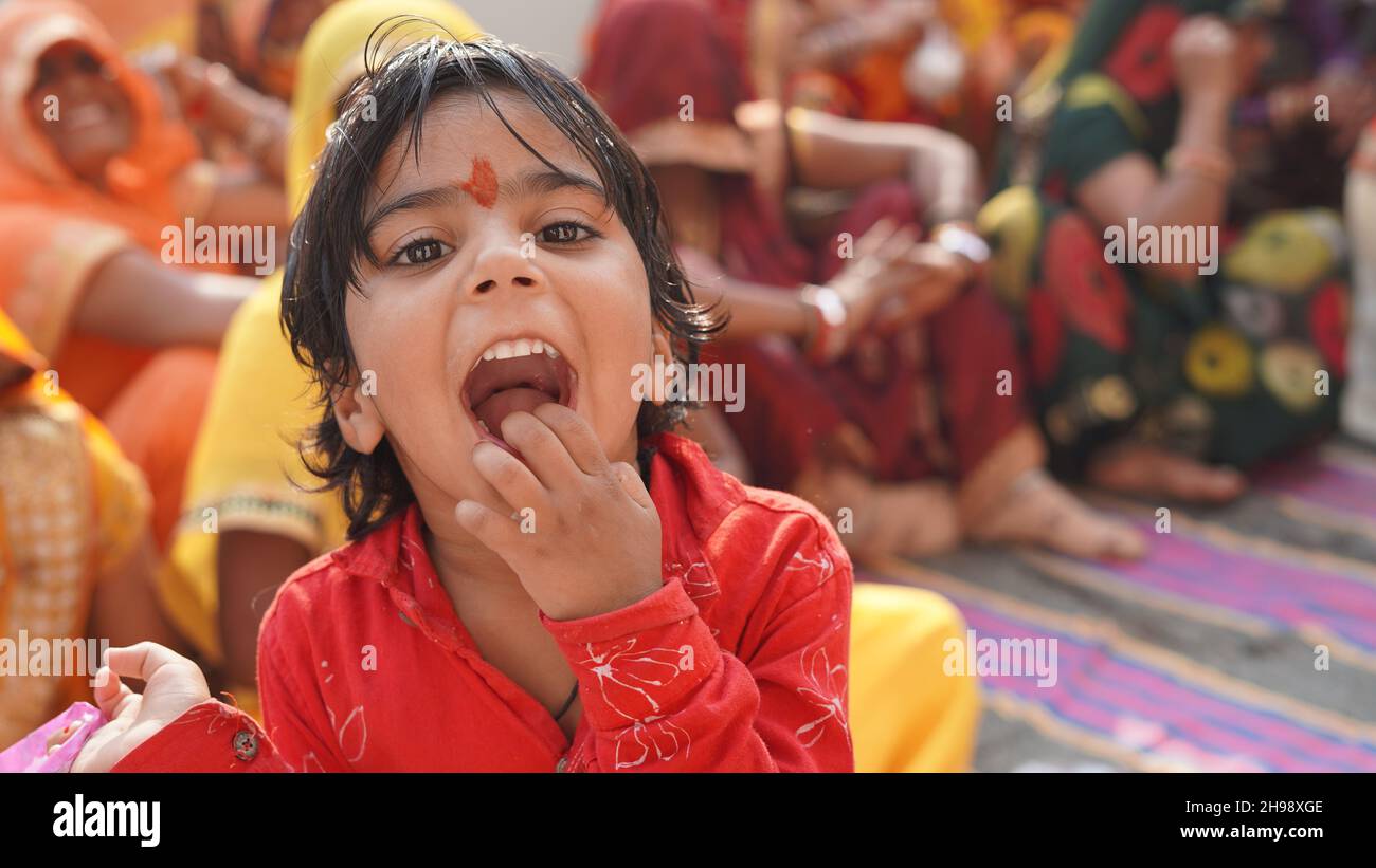 Carina e innocente ragazza asiatica in camicia rossa mostrando la sua bocca in una cerimonia di nozze. Foto Stock