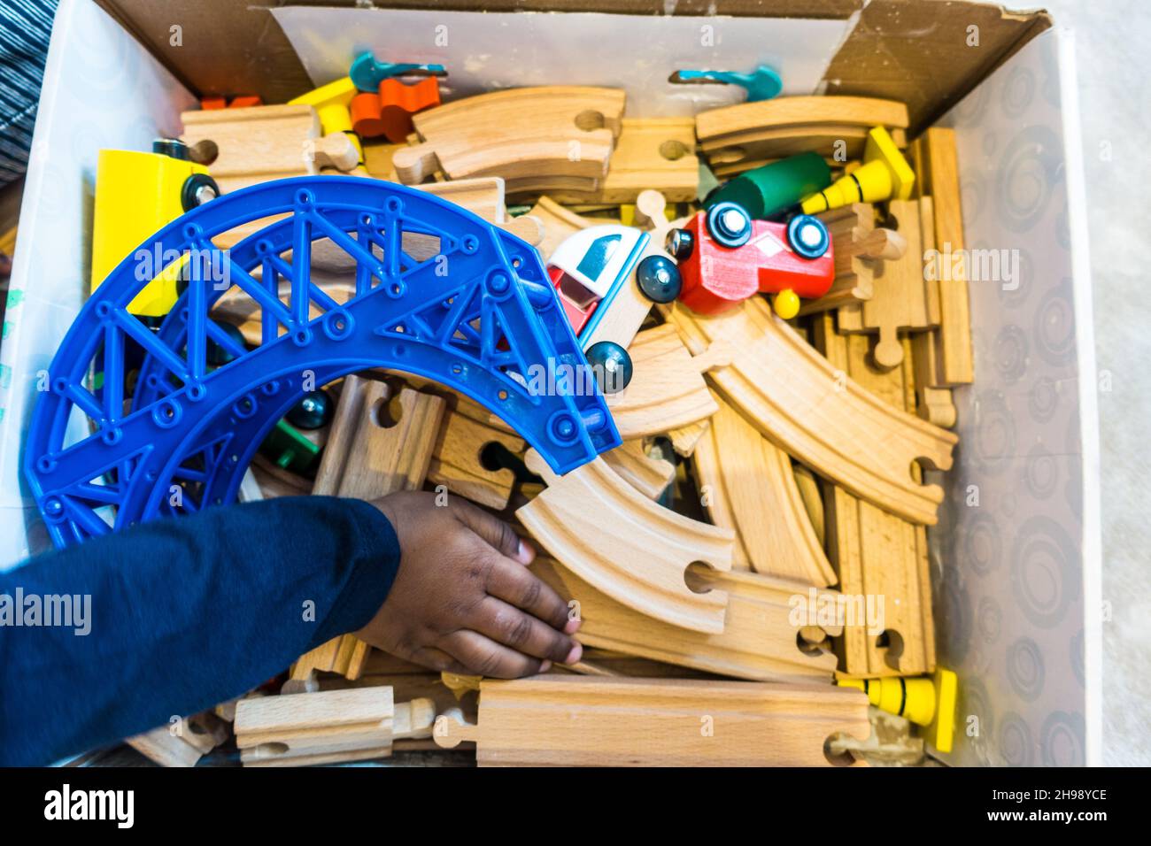 Ragazzo indiano di 3 anni che gioca con un treno di legno e treno set Foto Stock