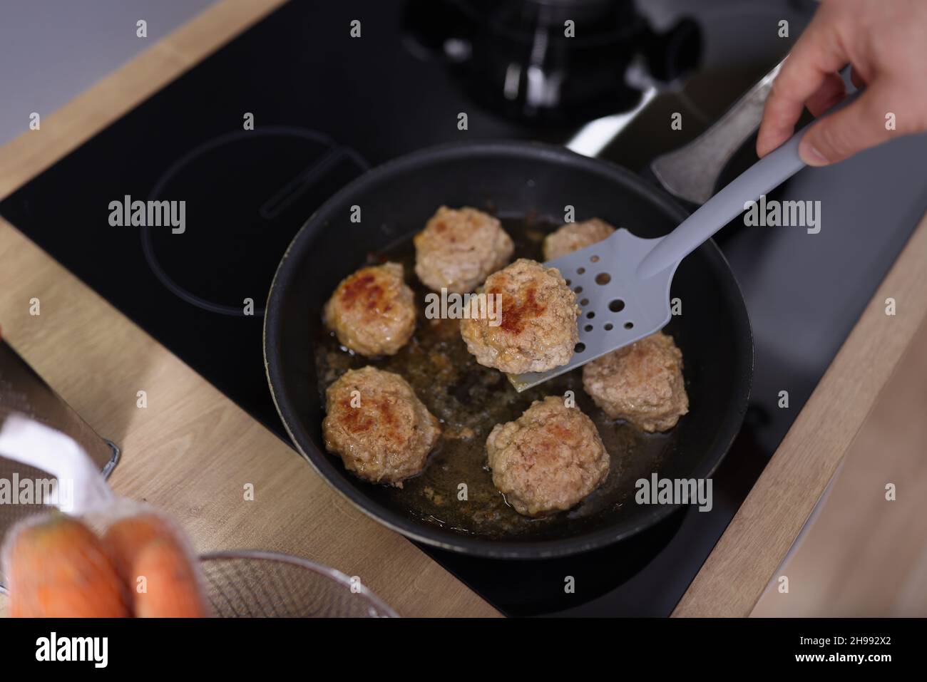 Palle di carne che iniziano a friggere in olio in padella sul piano cottura Foto Stock