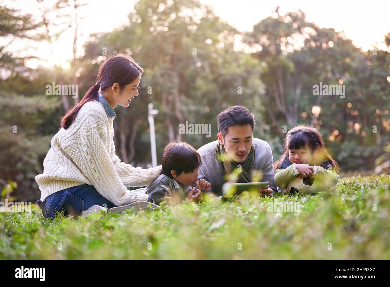 famiglia asiatica con due bambini che si rilassa all'aperto nel parco cittadino Foto Stock