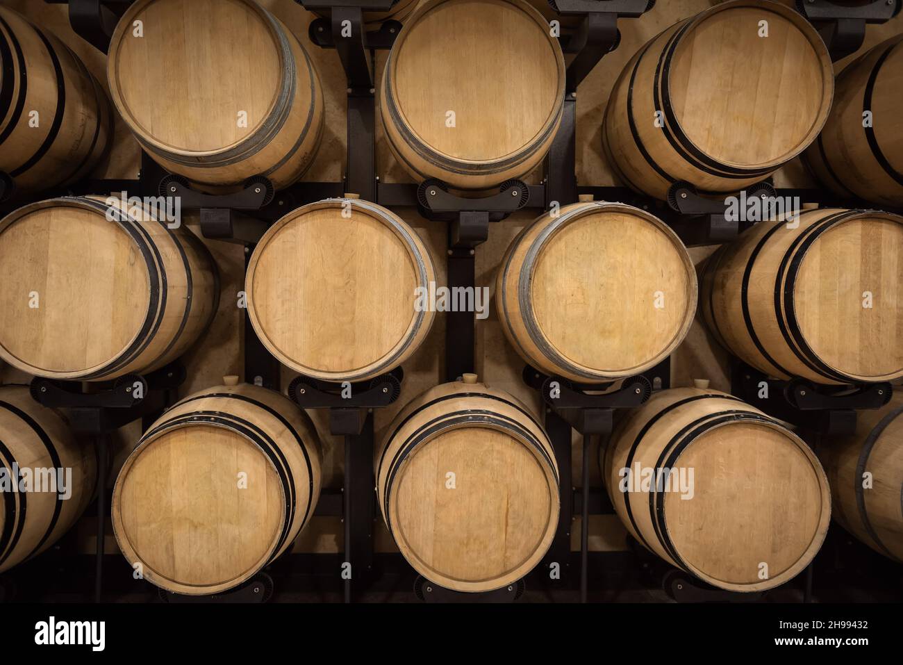 Botti con vino rosso nella volta della cantina, background di produzione del vino Foto Stock