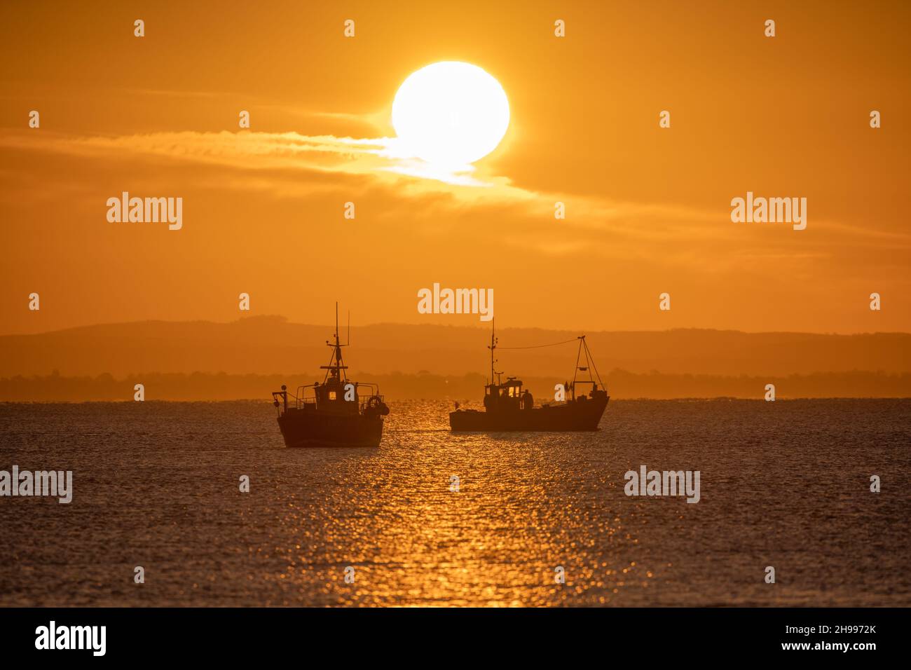 Due barche da pesca in attesa di uscire al sole di mattina presto al largo della costa di Selsey nel Sussex occidentale Foto Stock