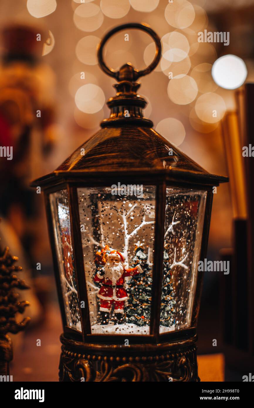 Lanterna magica con composizione invernale natalizia con albero di Natale e giocattolo Babbo Natale. Installazione di Capodanno per le vacanze invernali con lig bokeh dorato Foto Stock