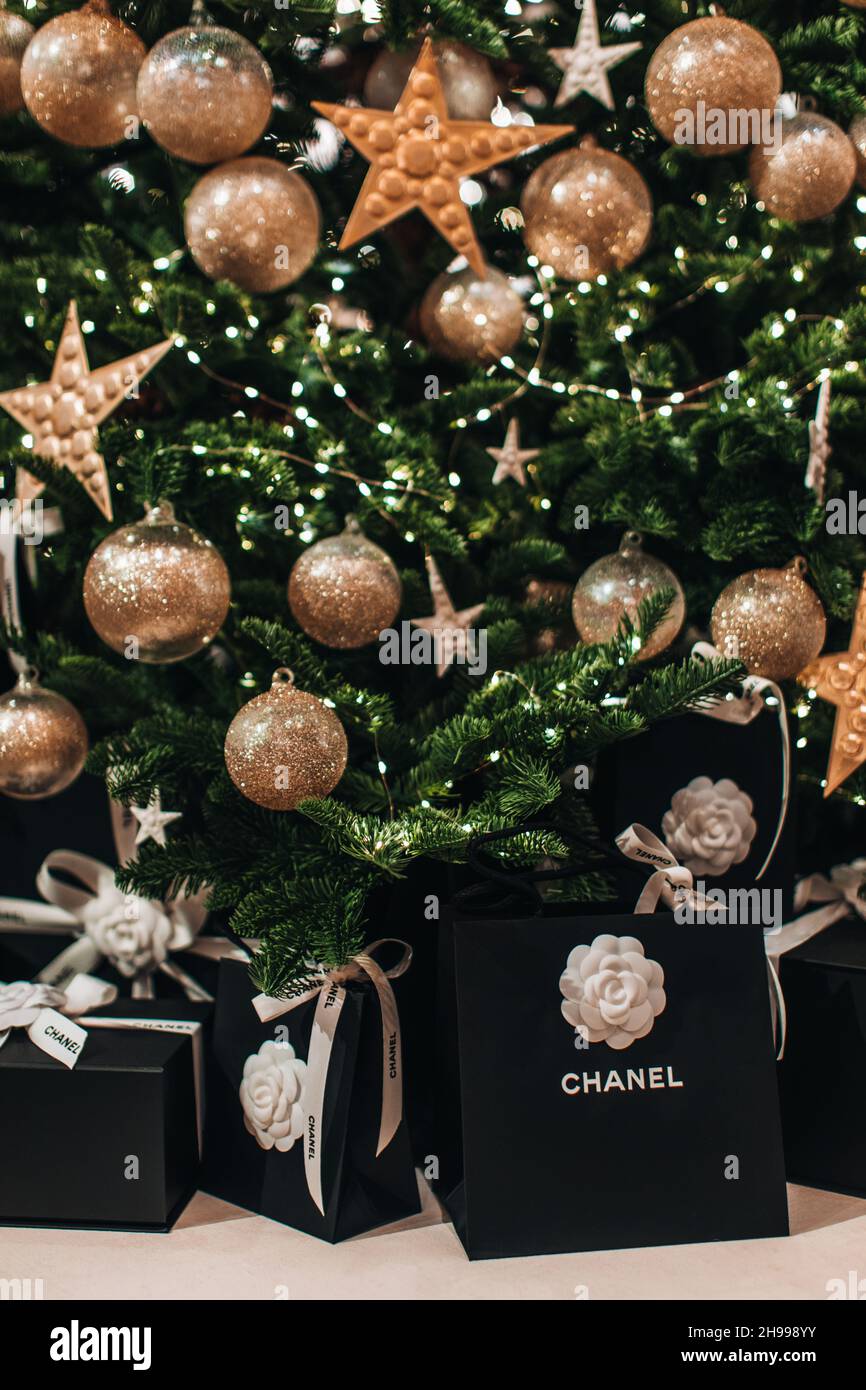 Borsa nera regalo di festa Chanel con nastri bianchi setosi sotto l'albero di Natale con palle dorate di Natale. Capodanno regali di lusso Foto Stock