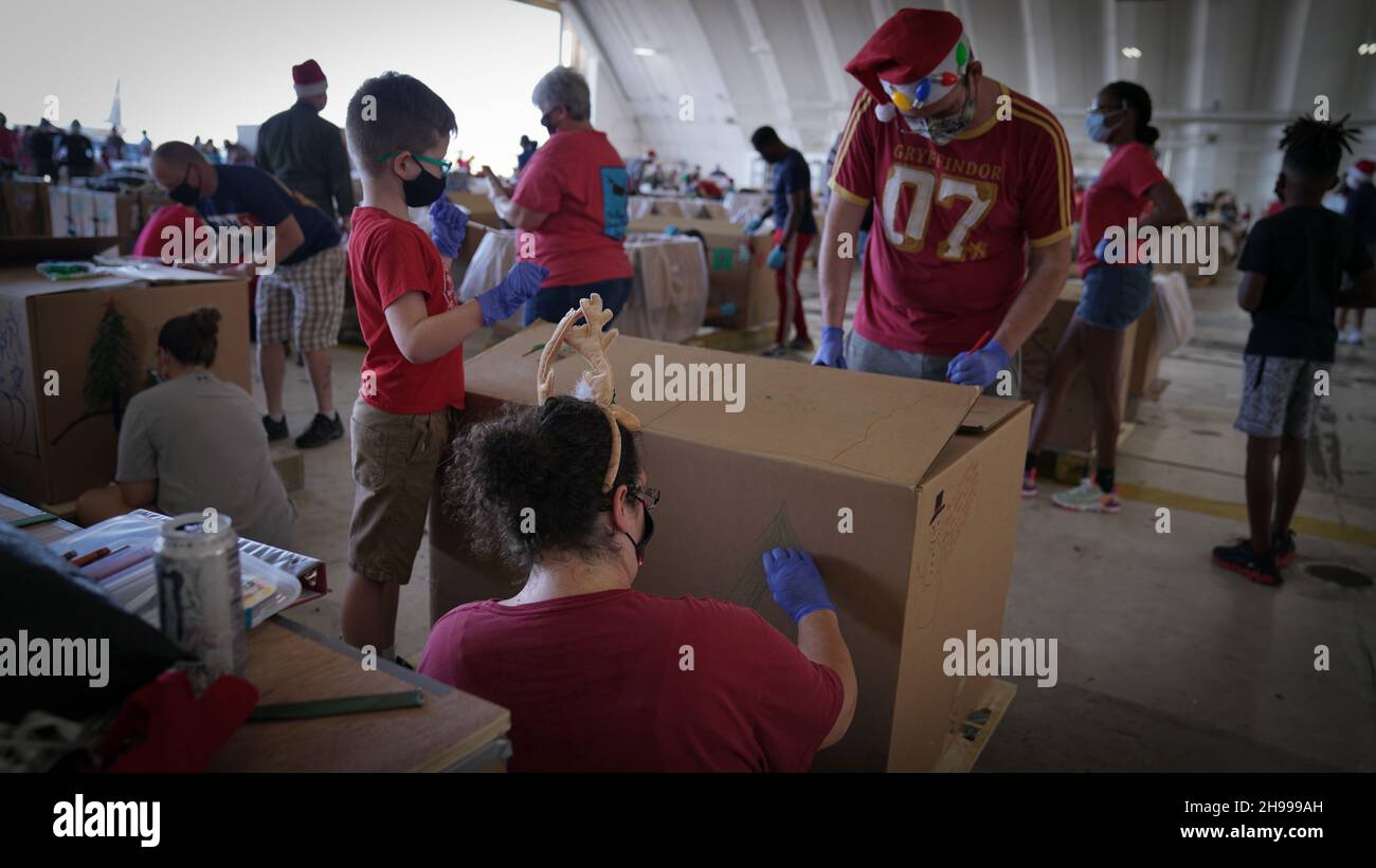 Yigo, Stati Uniti. 4 dicembre 2021. I volontari imballano le merci donate e decorano i pacchetti airdrop con i messaggi a sostegno della 70a operazione annuale di Natale drop alla base militare Andersen 4 dicembre 2021 a Yigo, Guam. Ogni dicembre, airdrop donerà cibo, forniture, materiale didattico e strumenti a 55 nazioni insulari in tutto il Pacifico sudorientale. Credito: 1 lt. Jade Watkins/US Airforce Photo/Alamy Live News Foto Stock