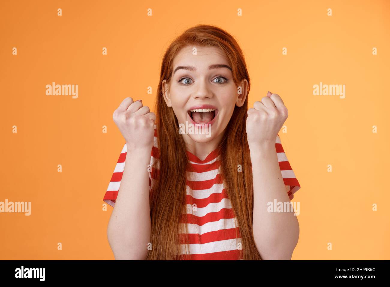 Primo piano eccitata ottimista redhead fortunata ragazza vincitrice primo premio punteggio goal, sorridente ampiamente ricevere un risultato eccellente, pompa pugnale trionfante, stupito Foto Stock