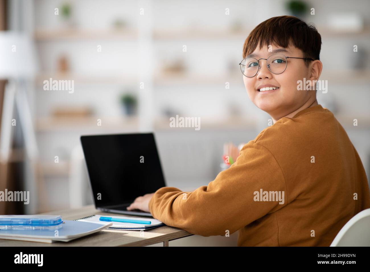 Bambino cinese allegro usando il laptop con schermo vuoto Foto Stock