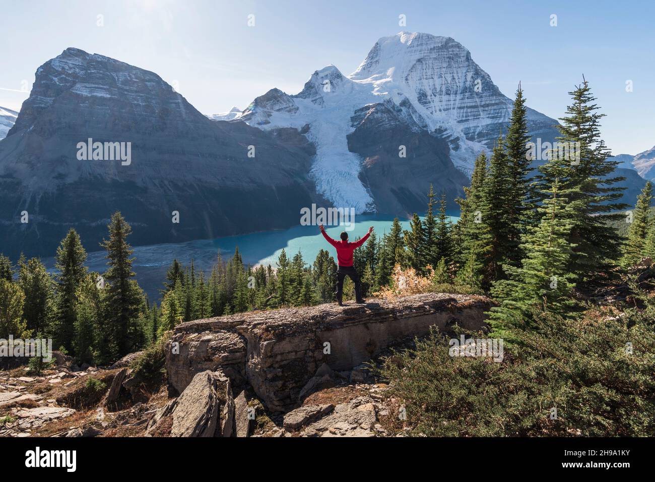 Uomo con le braccia sollevate, su una cresta sopra il lago di Berg e le montagne. Foto Stock