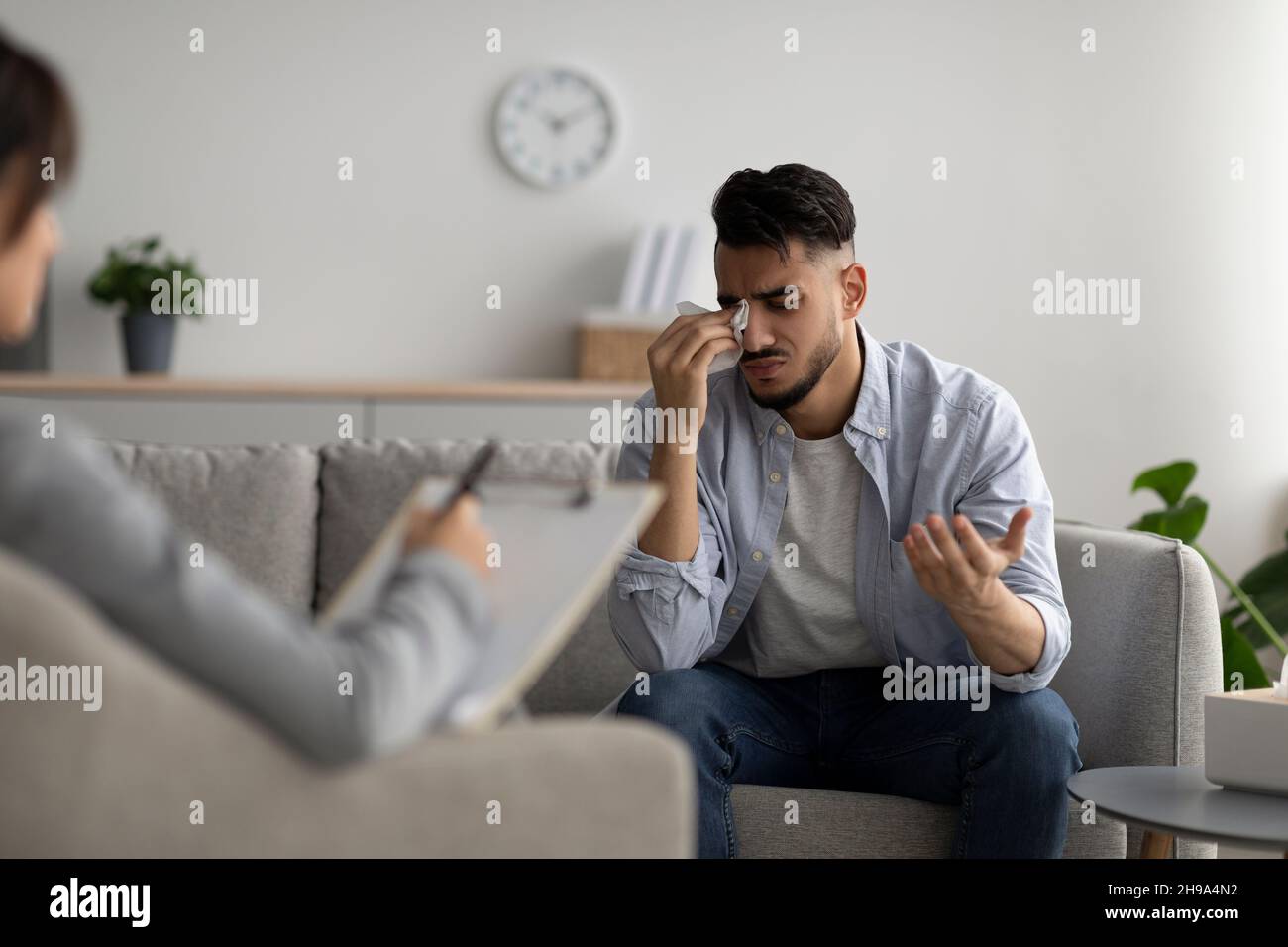 Depresso il ragazzo medio-orientale piangendo all'ufficio dello psicoterapeuta, cercando aiuto professionale, condividendo i suoi problemi Foto Stock