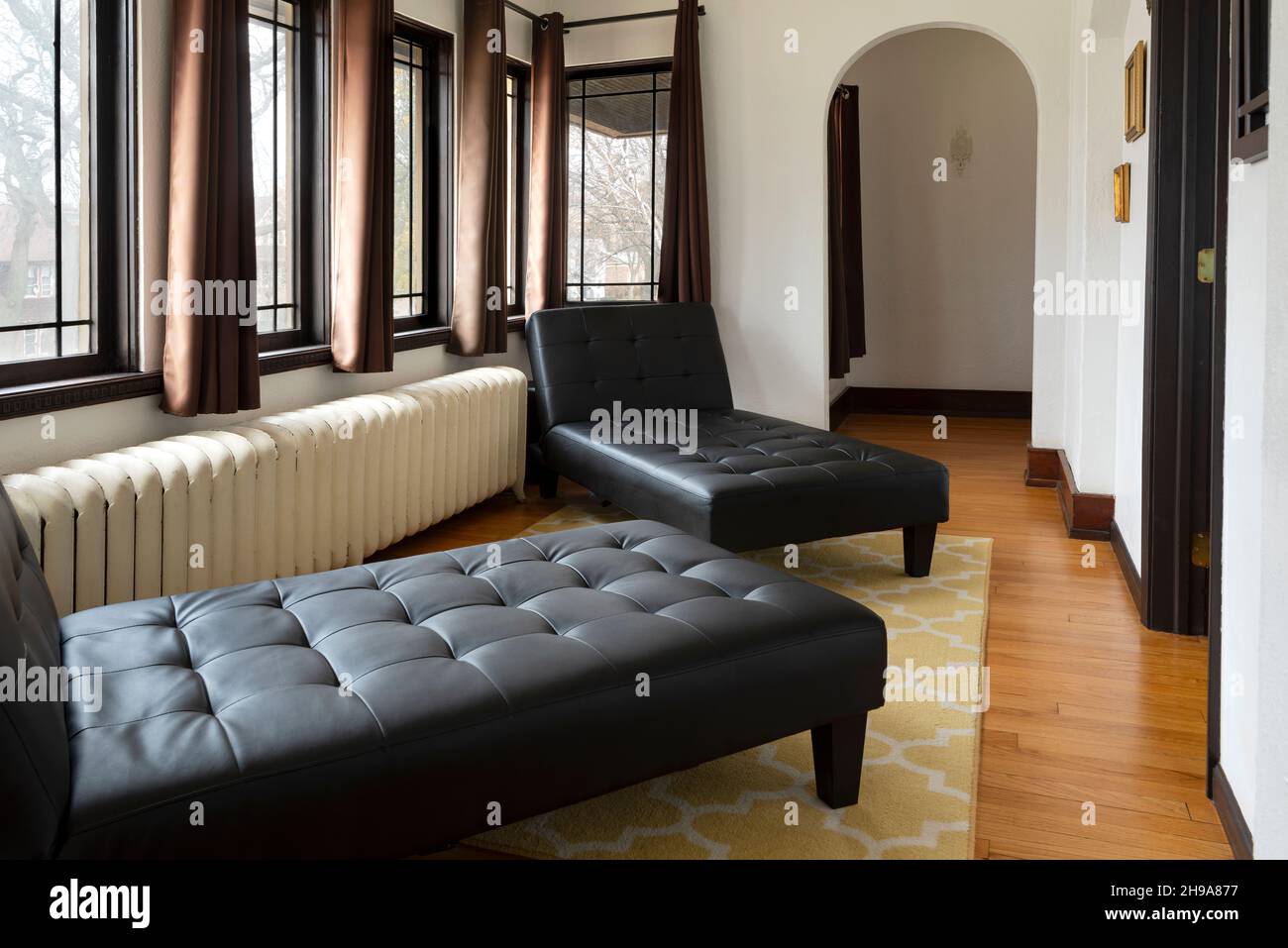 interni arredati di casa con sedie a sdraio, finestre e tende disegnate con pavimento in legno aperto e rivestimento del pavimento Foto Stock