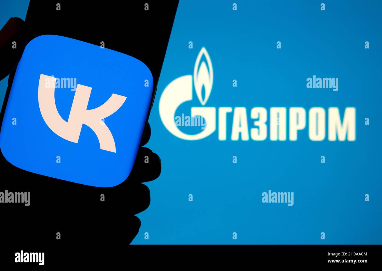 Logo dell'app VK visualizzato su uno smartphone e logo GAZPROM sul laptop sfocato. Parola in russo tradita come 'GAZPROM'. Concetto. Stafford, Regno Unito, De Foto Stock