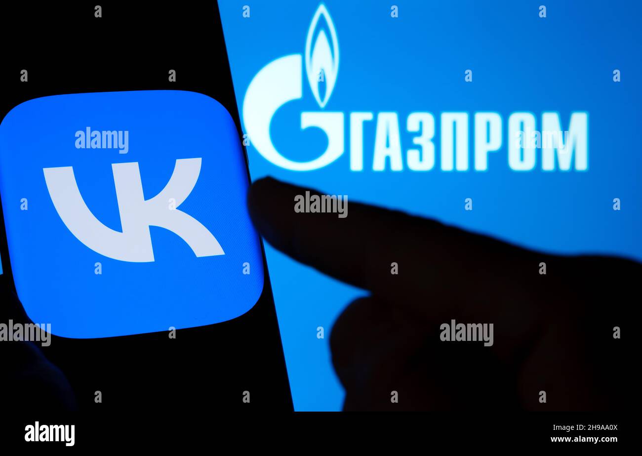 Logo dell'app VK visualizzato su uno smartphone e logo GAZPROM sul laptop sfocato. Parola in russo tradita come 'GAZPROM'. Concetto. Stafford, Regno Unito, De Foto Stock