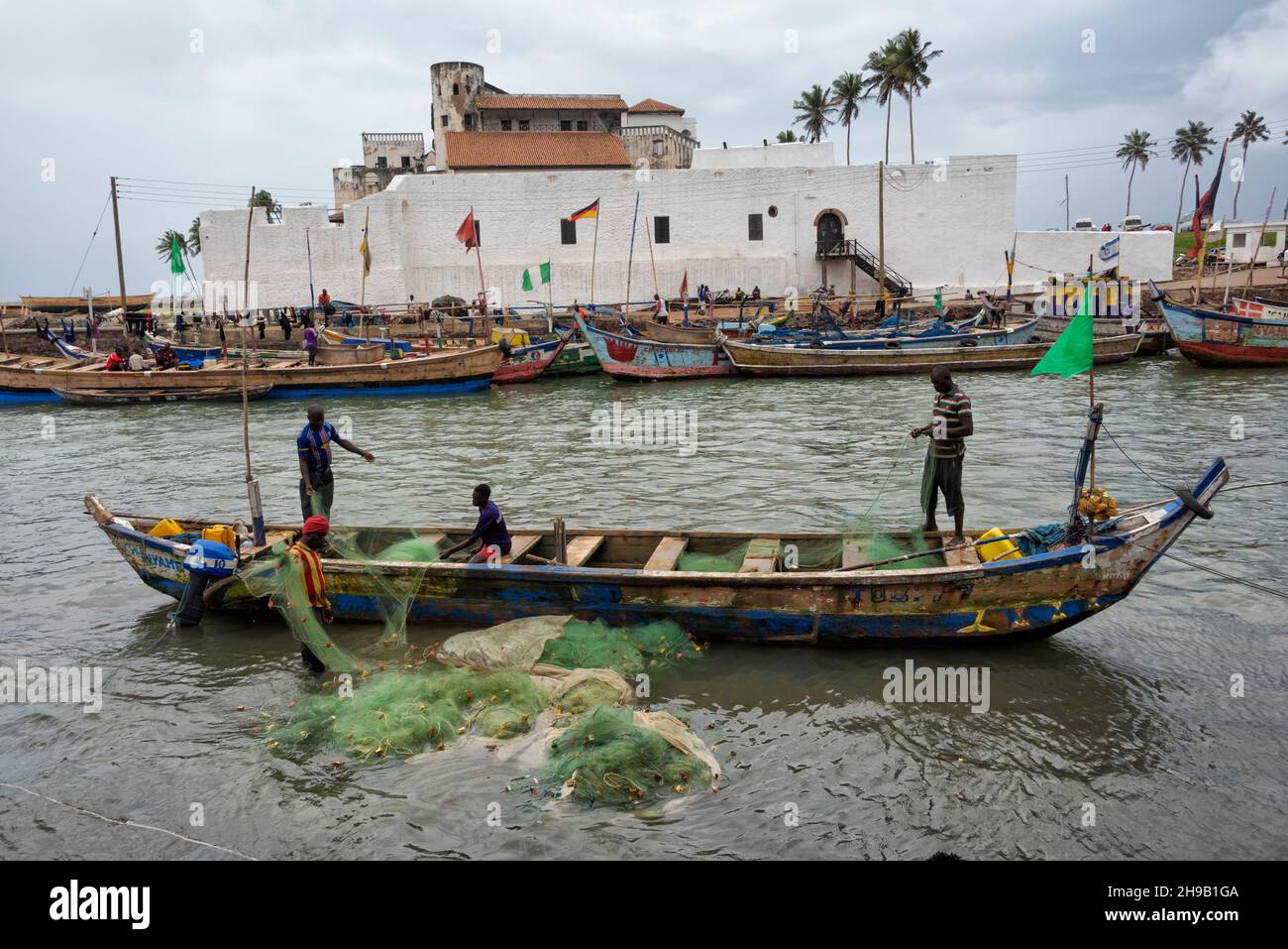 Castello di Elmina (Castello di San Giorgio/Forte di San Jorge), patrimonio dell'umanità dell'UNESCO, con barche da pesca nel porto, Elmina, Regione Centrale, Ghana Foto Stock