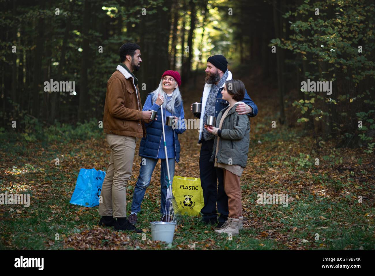 Un gruppo di volontari felici che puliscono la foresta, che si rompono, bevono il tè e parlano insieme. Foto Stock