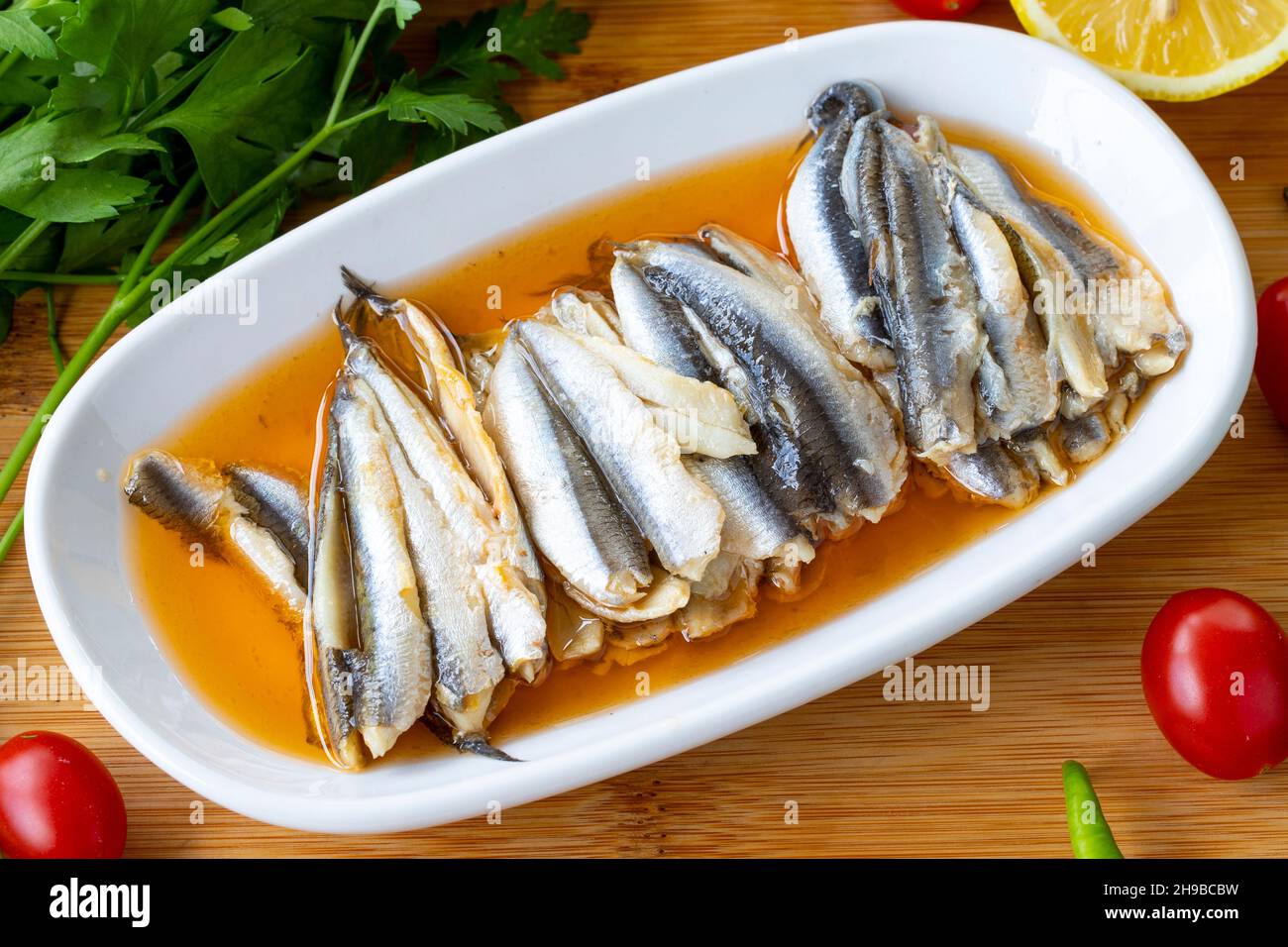 Acciughe marinate da vicino su sfondo di legno. Piatti di pesce. Acciuga con salsa di nome locale Foto Stock