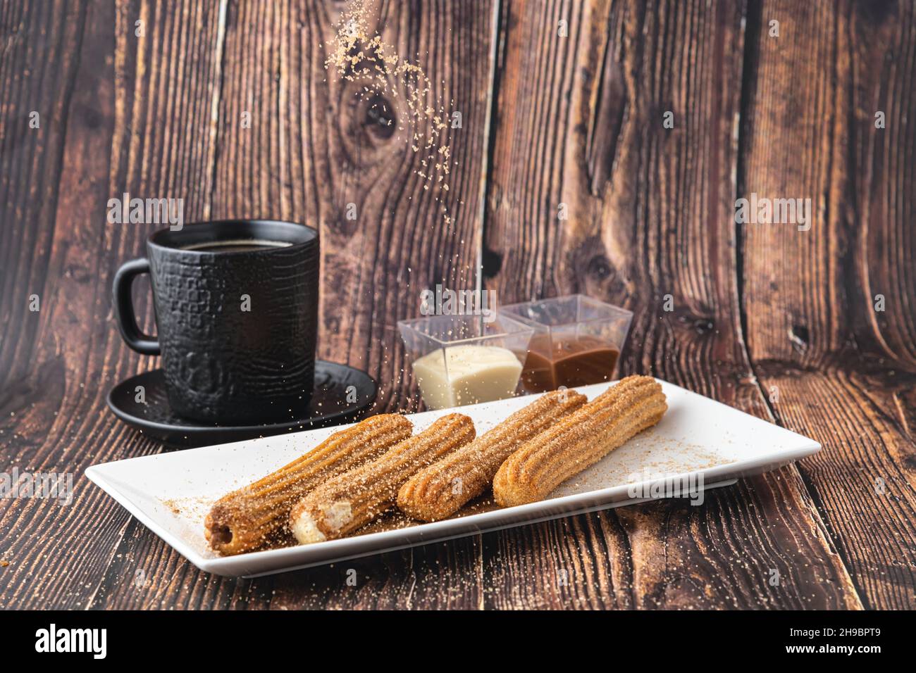 Churros caldi con salsa di cioccolato su tavola di legno. Foto Stock