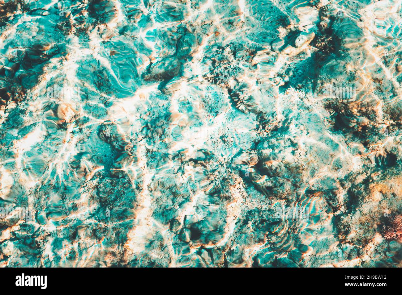 La superficie bianca blu dell'acqua lacerata con le onde e il sole bello scintilla sopra le barriere coralline Foto Stock
