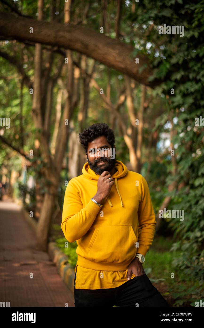 Bel modello maschile in un parco pubblico, modello maschile indiano con sfondo verde Foto Stock