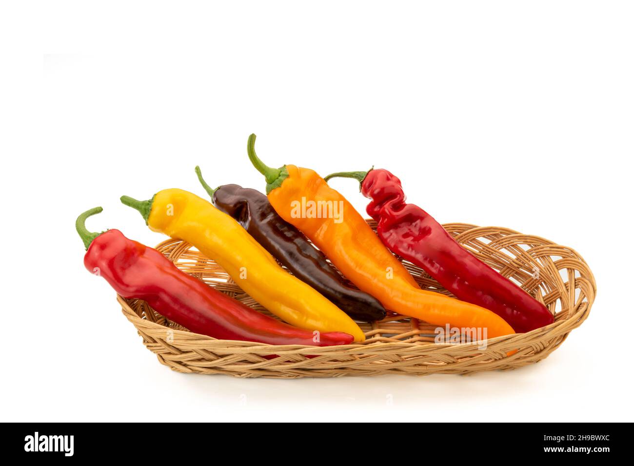 Peperoni colorati chiamati corna di bue nel cestino di vimini isolato su bianco, spazio copia Foto Stock