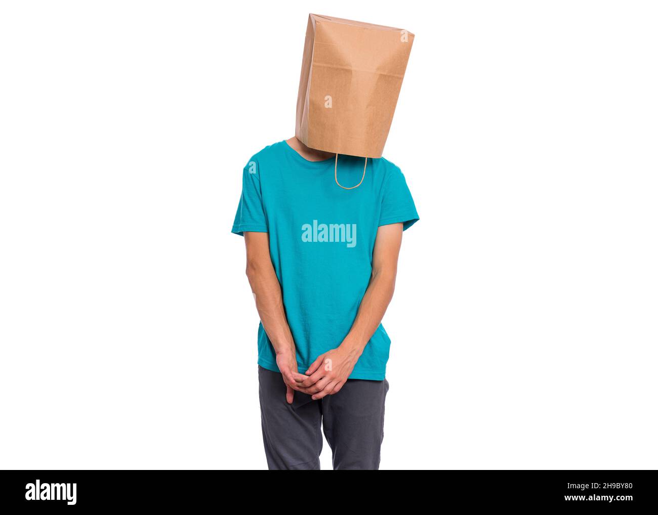 Il ragazzo modesto con il sacchetto di carta sulla testa tiene le mani. Shy Teenager isolato su sfondo bianco. Foto Stock