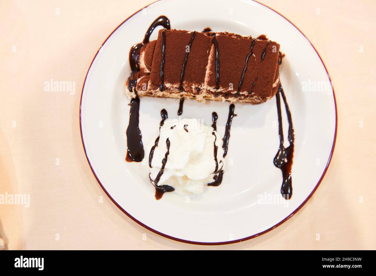 Tiramisù su piatto bianco con crema e cioccolato, dessert italiano. Chiudi vista Foto Stock