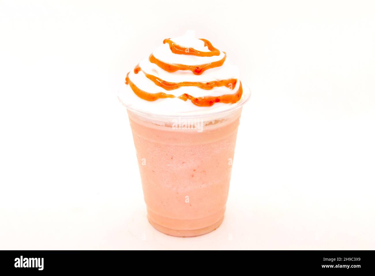 Agitare il latte alla fragola con lo sciroppo, sgocciolato sulla panna montata in una tazza di plastica usa e getta. Foto Stock