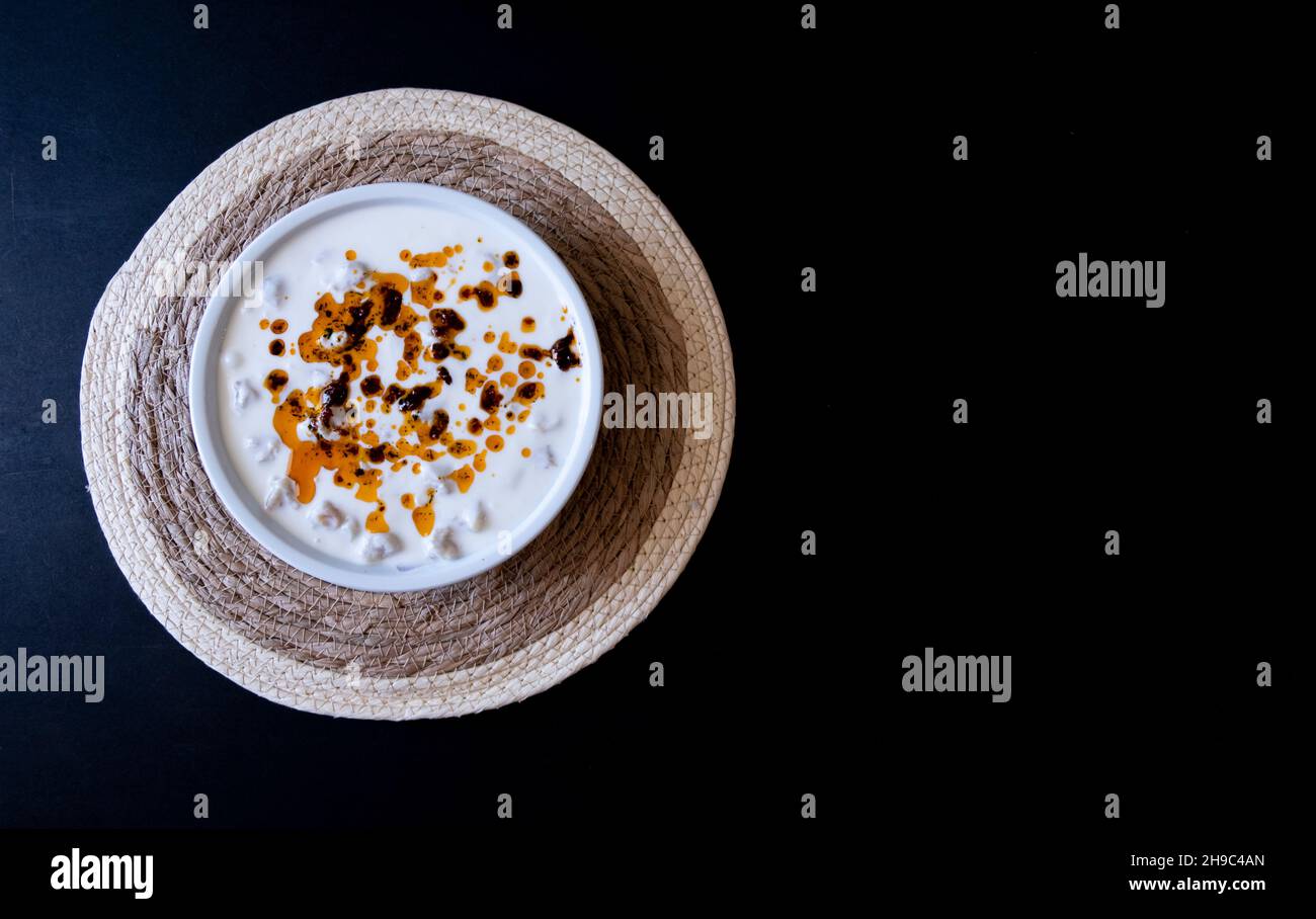 Manti turchi con pepe rosso, salsa di pomodori, yogurt e menta, ravioli turchi in piatto bianco su sfondo nero isolato Foto Stock