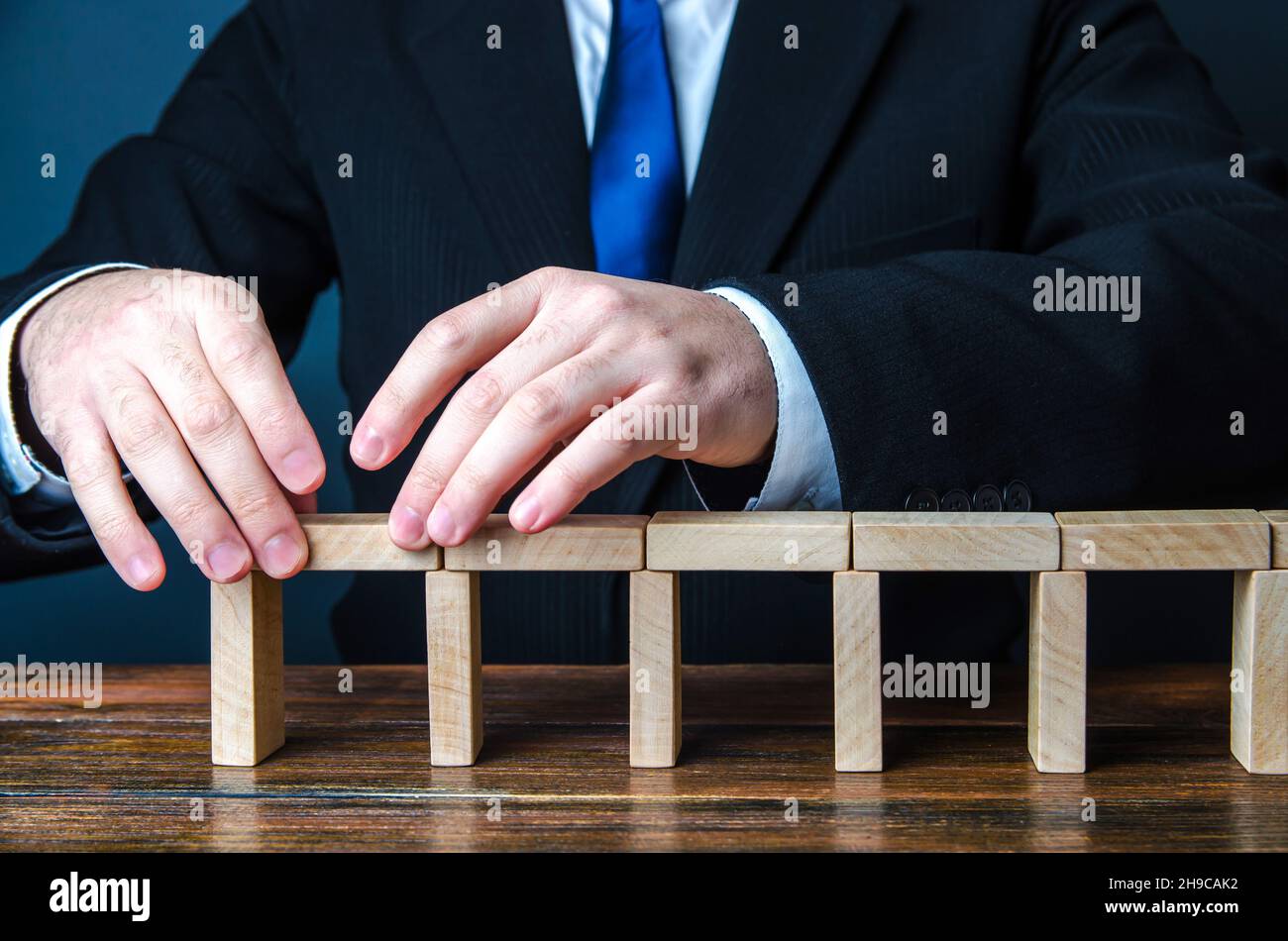 Un uomo che costruisce un ponte di blocchi di domino. Pianificazione strategica espansione aziendale. Sviluppo e progressione. Leadership. Creare, progettare, espandere un comp Foto Stock