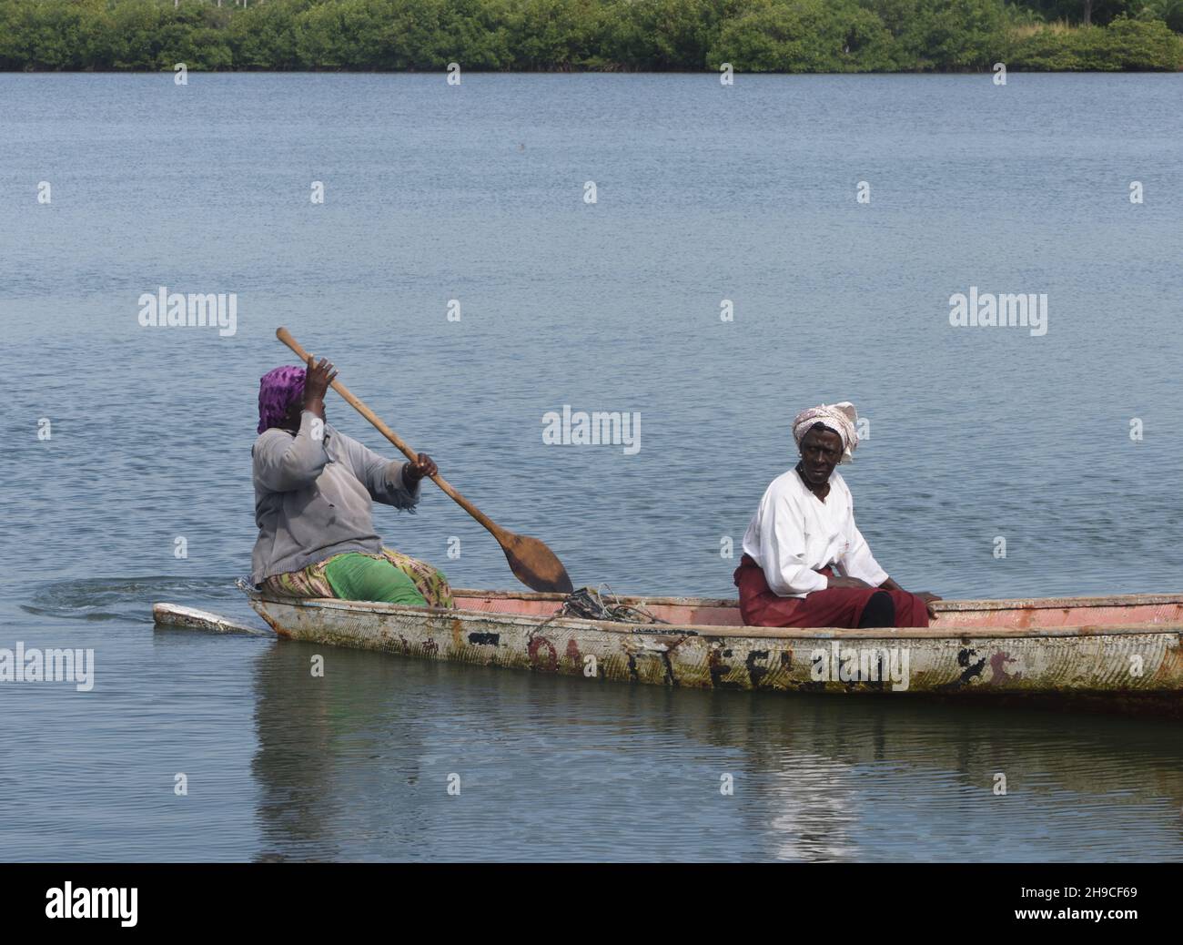 Due donne in canoa pagaia lungo il fiume San Pedro che forma il confine meridionale con il Senegal. Kartong, Repubblica della Gambia. Foto Stock