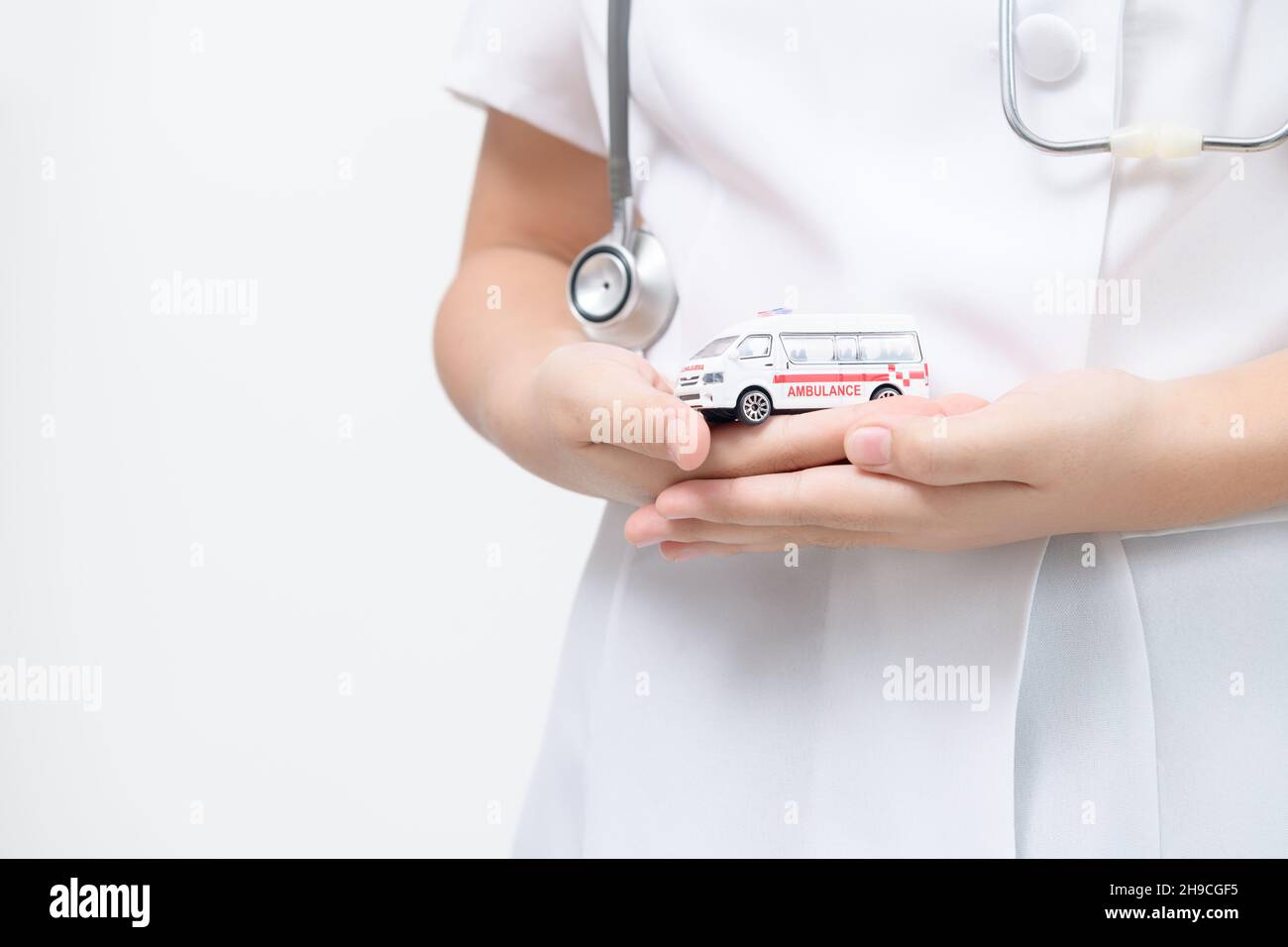 Modello di ambulanza in mano del medico isolato su sfondo bianco, servizio di trasferimento del paziente o concetto di assicurazione Foto Stock