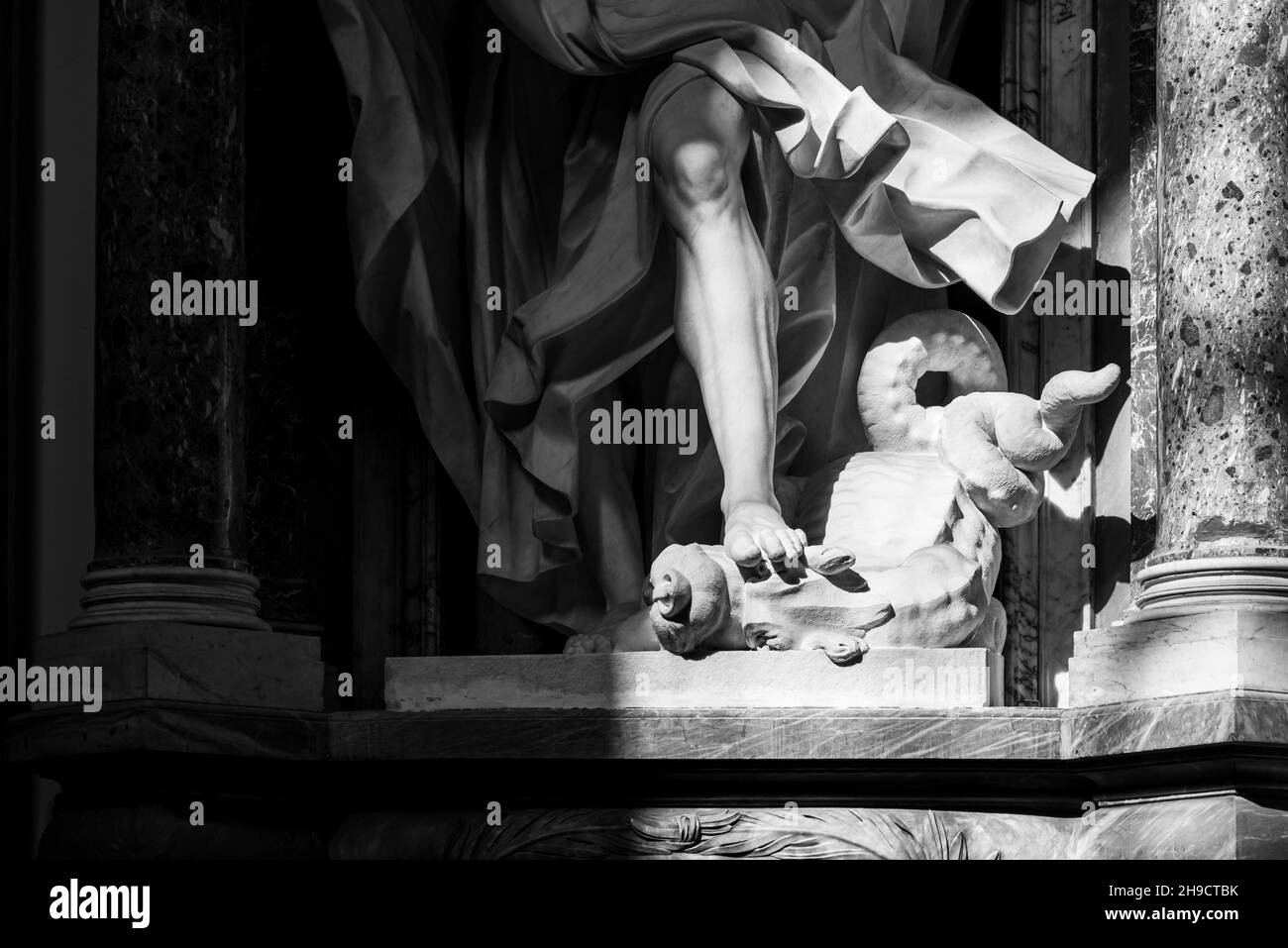 Foto in bianco e nero che mostra in dettaglio statue di marmo raffiguranti un piede maschio che strapa la testa di una bestia mitologica Foto Stock